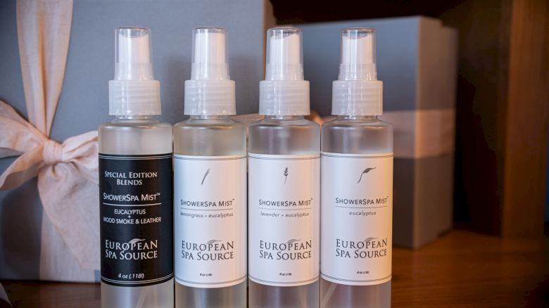 Four bottles of ShowerSpa Mist by European Spa Source are lined up in front of a ribbon-wrapped gift box.